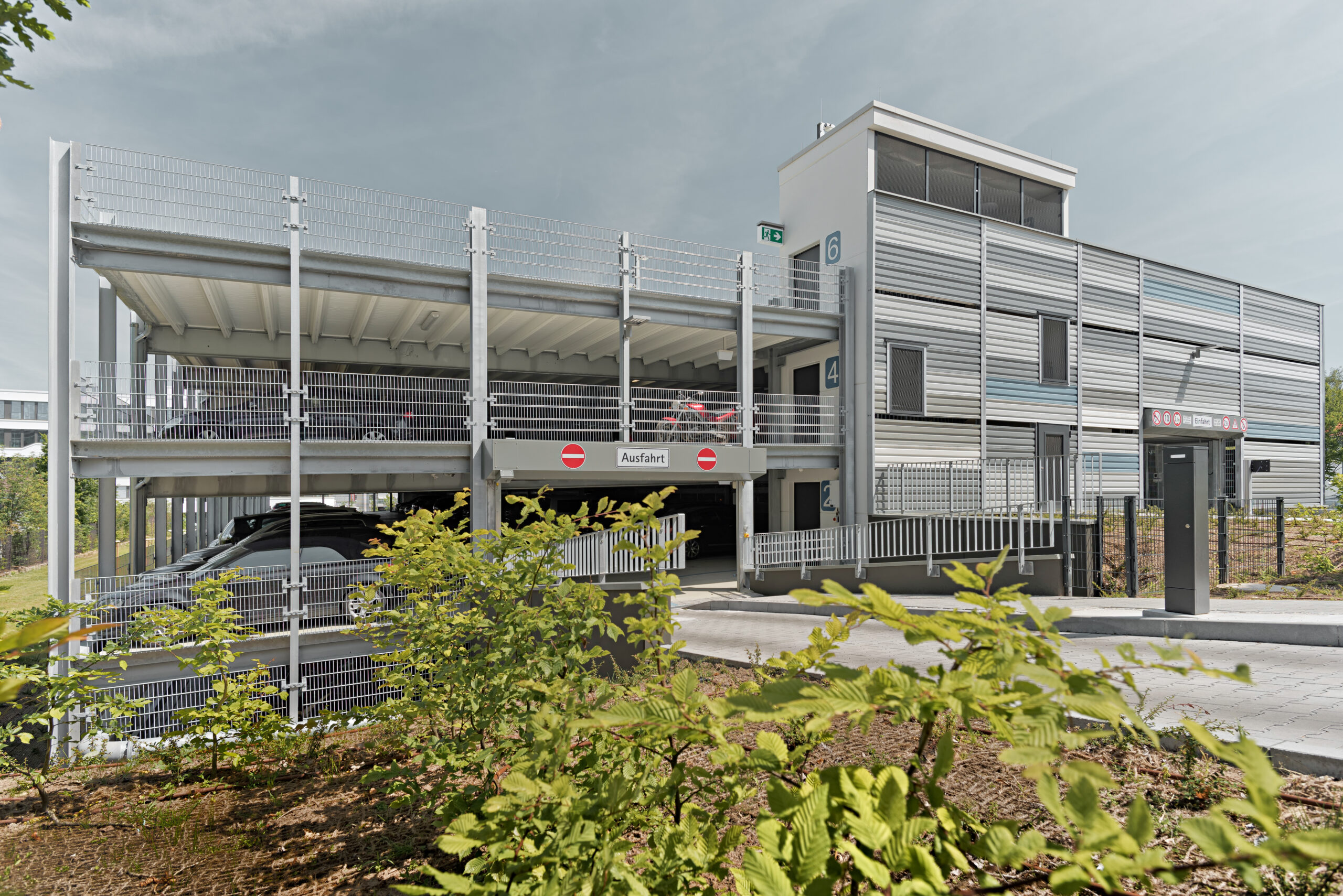 Einfahrt und Erschließung des Parkhauses mit klarer Beschilderung und offener Stahlkonstruktion.
