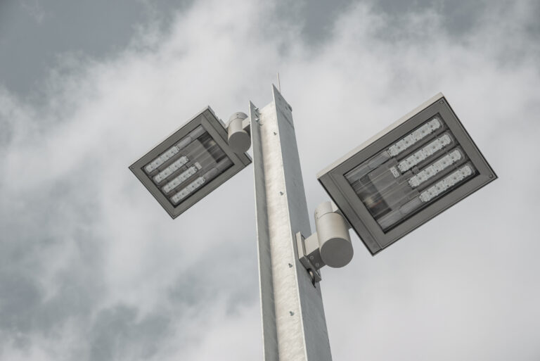Detailaufnahme eines LED-Lichtmasts mit zwei Leuchten vor bewölktem Himmel.