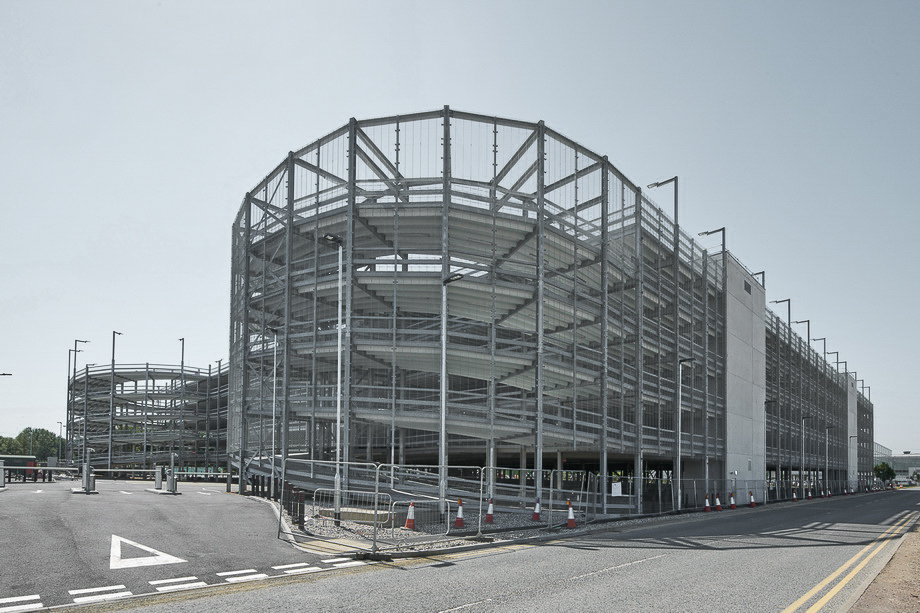 Außenansicht eines offenen Parkhauses mit Stahlkonstruktion und spiralförmiger Rampe.