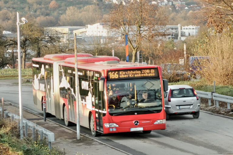 Roter Linienbus auf einer Straße nahe einem Park-and-Ride-Parkplatz.