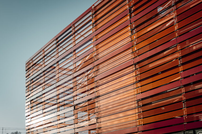 Detailansicht der orangefarbenen Metalllamellenfassade.