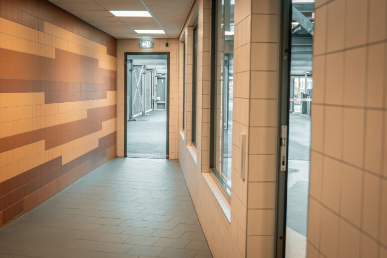 Fußgängerbereich im Parkhaus Gouda mit gefliesten Wänden und Zugang zum Parkdeck.