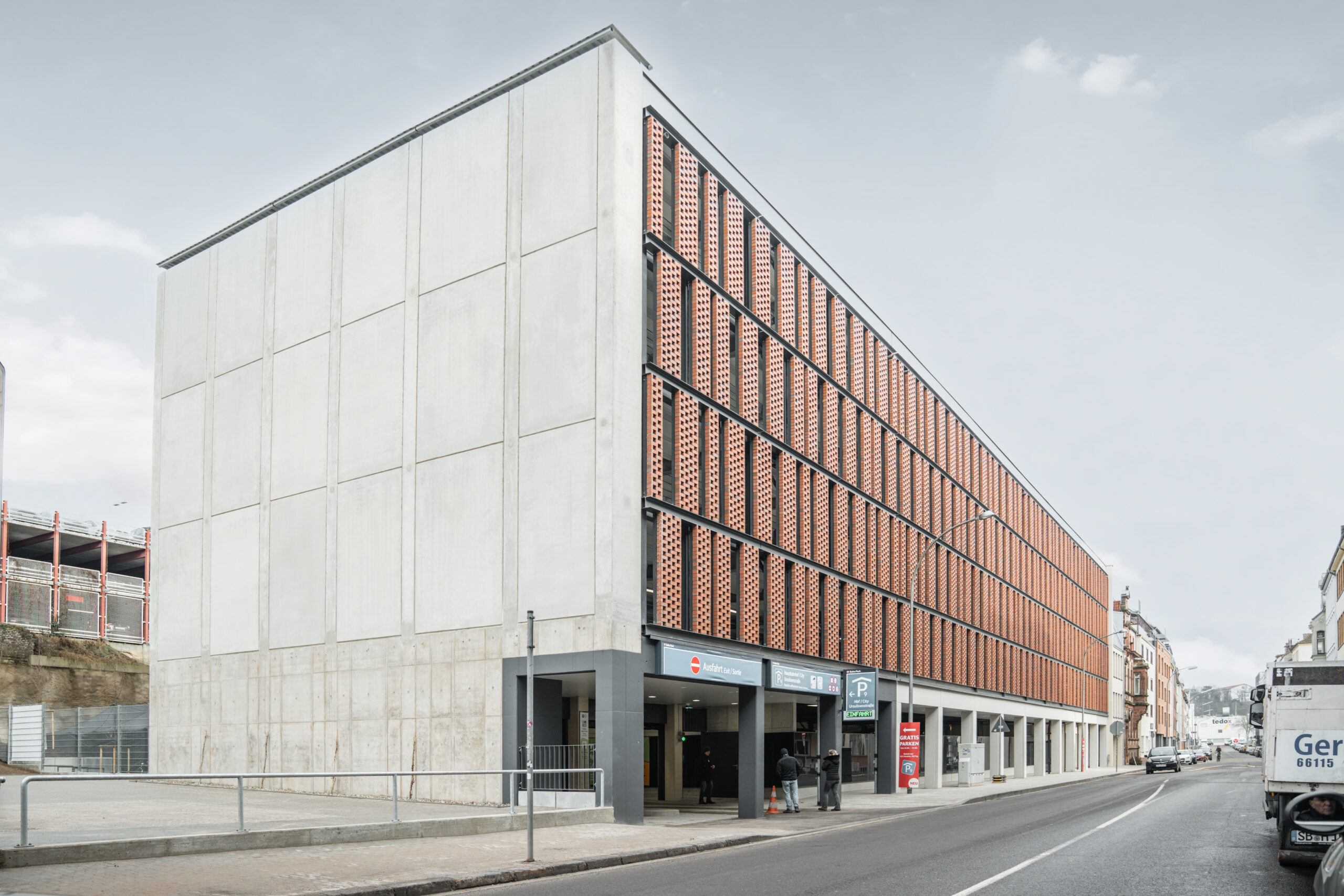 Seitlicher Sicht eines Parkhauses entlang einer Straße in Saarbrücken mit Ziegelfassade.