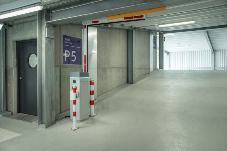 Ein- und Ausfahrtskontrolle im Parkhaus mit automatischer Schrankenanlage, Zufahrtsrampe und klarer Beschilderung.