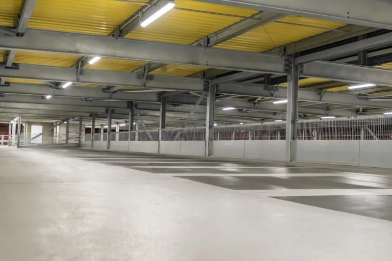 Parkdeck mit Stahlkonstruktion, Beleuchtung und markierten Stellplätzen.
